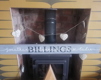 May include: A grey wooden sign with the text "Jonathan Billings Lynn Lab & Eadie" written in white cursive script. The sign is decorated with a string of white hearts with black polka dots hanging above it.