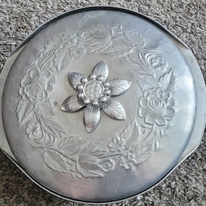 May include: Silver serving dish with a floral design and a decorative flower-shaped knob in the center.