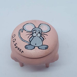May include: A pink ceramic trinket box with a mouse design. The mouse is gray with black eyes and whiskers. The box has three legs and the words "D.D. Speer" are written on the side.