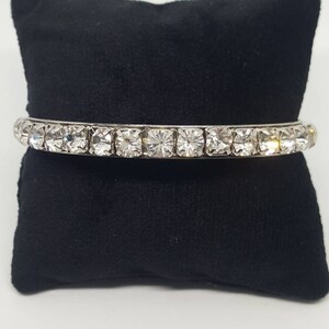 May include: A silver bangle bracelet with a row of clear rhinestones.