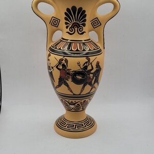 May include: A yellow ceramic vase with two handles and a black and red design of Greek warriors fighting. The vase has a decorative pattern around the top and bottom.