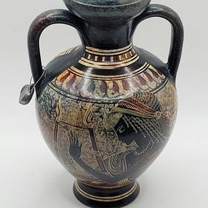 May include: A black and brown ceramic vase with two handles. The vase is decorated with a black and white image of a woman playing a lyre. The vase has a geometric pattern around the neck.