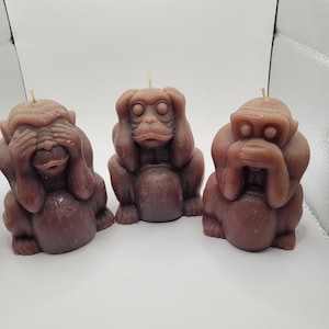 May include: Three brown monkey candles, each with a different gesture: one covering its eyes, one covering its ears, and one covering its mouth. The candles are made of wax and have a realistic monkey design.
