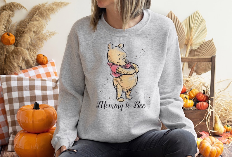 May include: A gray sweatshirt with a cartoon image of Winnie the Pooh and the text "Mommy to Bee".