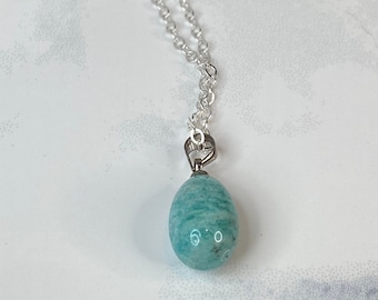 May include: A silver chain necklace with a light green, oval-shaped pendant made of amazonite.