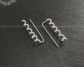 May include: A pair of silver ear cuffs with a spiral design. The cuffs are made of a thin wire that is twisted into a spiral shape. The spiral is about 1 inch long and has a slight curve to it. The cuffs are designed to be worn on the upper part of the ear, just above the lobe.