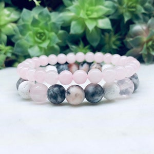 May include: Two beaded bracelets, one with pink and white beads and the other with pink, white, and grey beads.