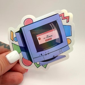 May include: A holographic sticker depicting a vintage computer monitor with an error message: "IDK TRY SCREAMING." The design includes pink, blue, green, and yellow geometric shapes. A fun, retro-themed sticker.