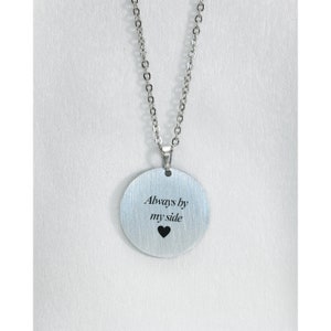 Pu&ograve; includere: Collana d'argento con un ciondolo rotondo che dice "Always by my side" con un piccolo cuore sotto il testo.