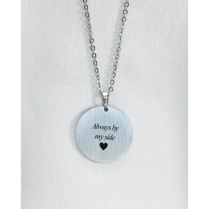 Pu&ograve; includere: Collana d'argento con un ciondolo rotondo che dice "Always by my side" con un piccolo cuore sotto il testo.