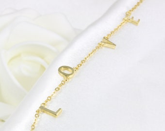 Könnte beinhalten: Eine goldene Kettenkette mit dem Wort "LOVE" in goldenen Buchstaben.