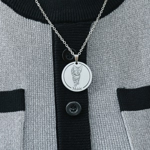 Pu&ograve; includere: Una collana d'argento con un ciondolo rotondo che presenta una foto in bianco e nero di un gatto. Il ciondolo &egrave; inciso con il nome "Maisie".