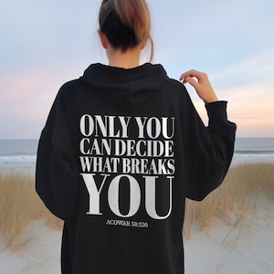 May include: Black hooded sweatshirt with the text "ONLY YOU CAN DECIDE WHAT BREAKS YOU" in white lettering on the back. The text is in a bold, sans-serif font. The text "ACOWAR 58:530" is printed in smaller white lettering below the main text.