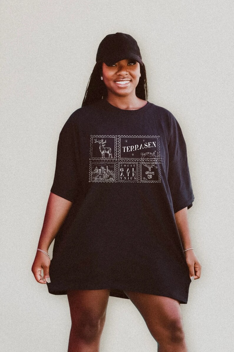 May include: A black oversized t-shirt with a graphic print of four postage stamps featuring a deer, a castle, a gate, and a unicorn. The text "TERRASEN" is printed on one of the stamps.