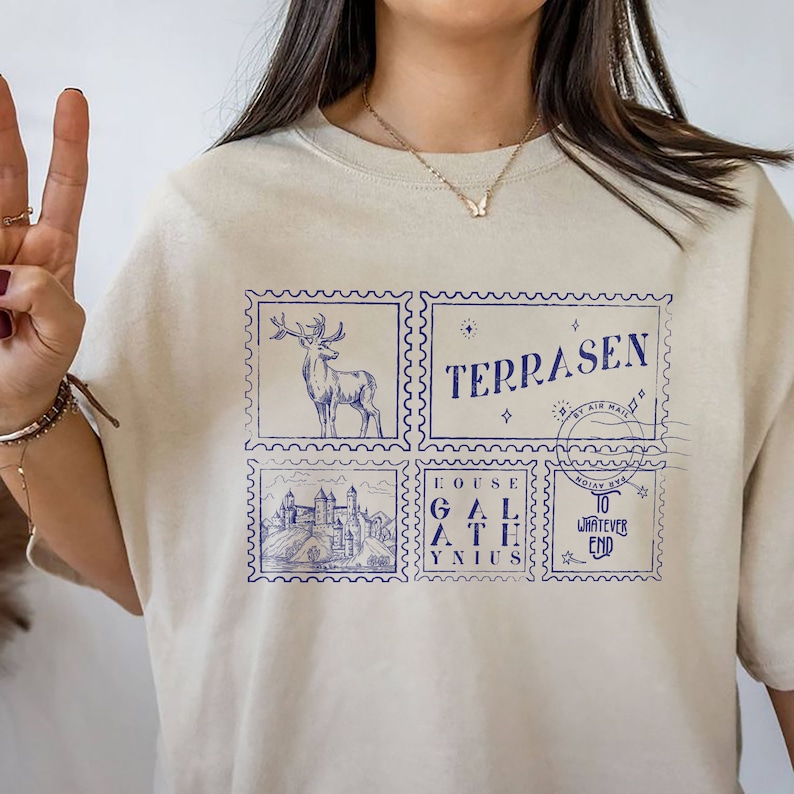 May include: Beige t-shirt with a blue graphic print of four postage stamps. The stamps feature a deer, a castle, the text "House Galathynus", and the text "Terrasen by Air Mail Noxian Xya to Whatever End".