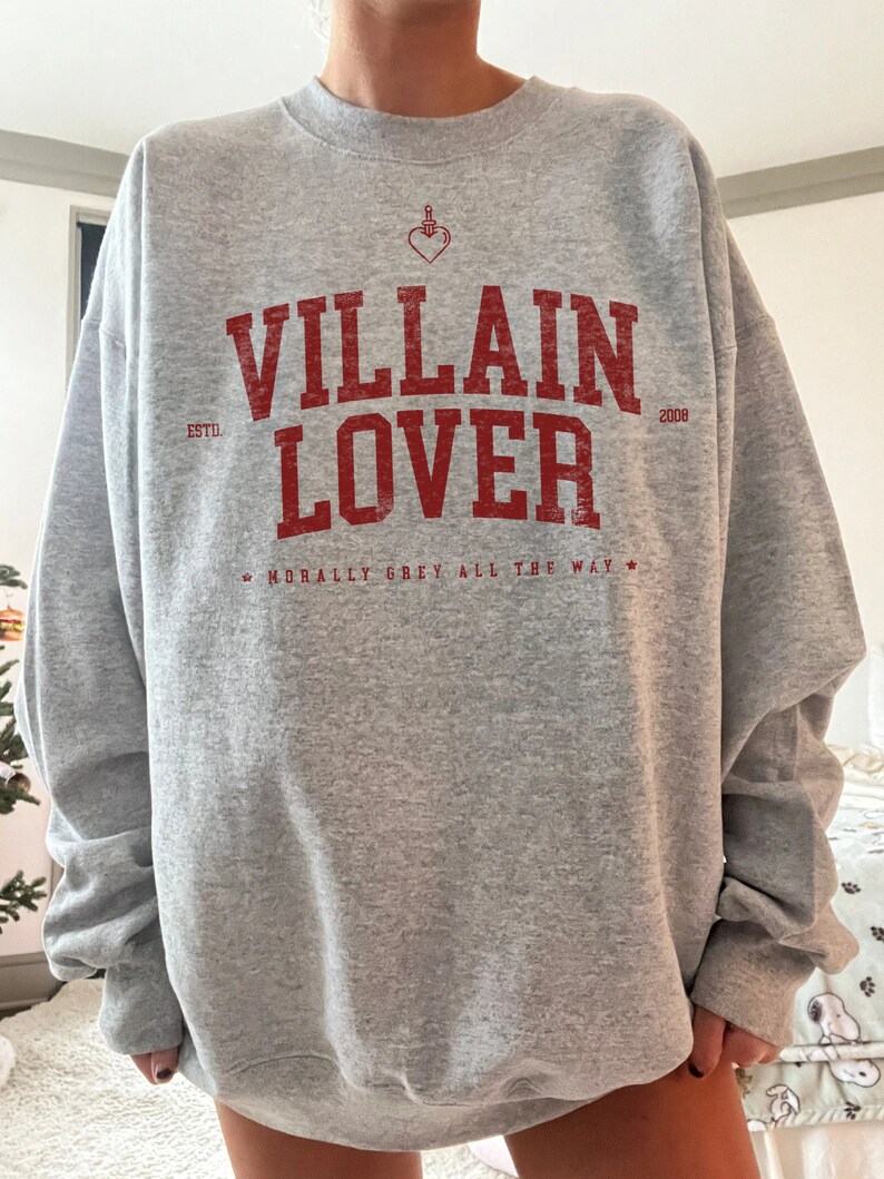 May include: Grey sweatshirt with a red graphic print that says "VILLAIN LOVER" with the text "ESTD 2008" and "MORALLY GREY ALL THE WAY" underneath.