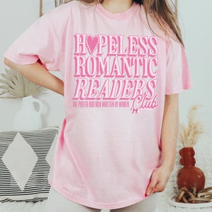 May include: Pink t-shirt with the text "Hopeless Romantic Readers Club" and the smaller text "We prefer our men written by women".
