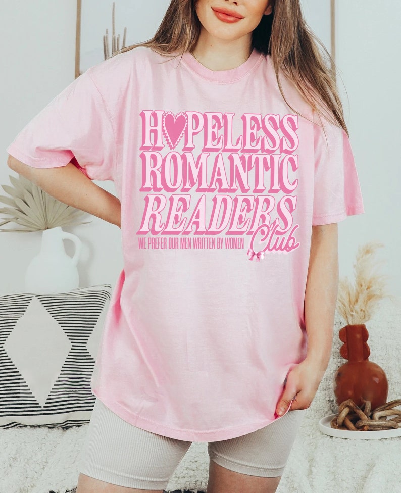 May include: Pink t-shirt with the text "Hopeless Romantic Readers Club" and the smaller text "We prefer our men written by women".