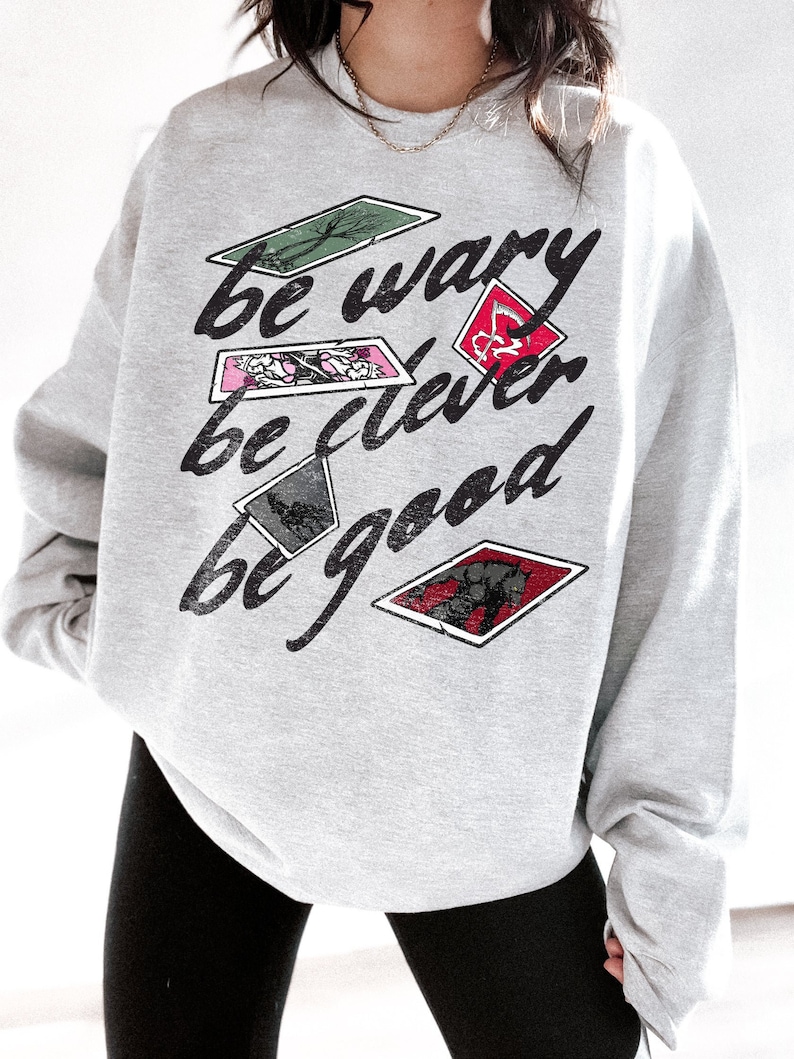 May include: Gray sweatshirt with a graphic print of playing cards with the text "be wary be clever be good".