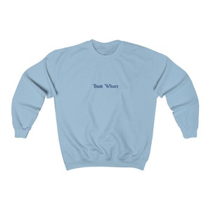 Puede incluir: Una sudadera de color azul claro con el texto "Book Whore" impreso en azul oscuro en la parte delantera.