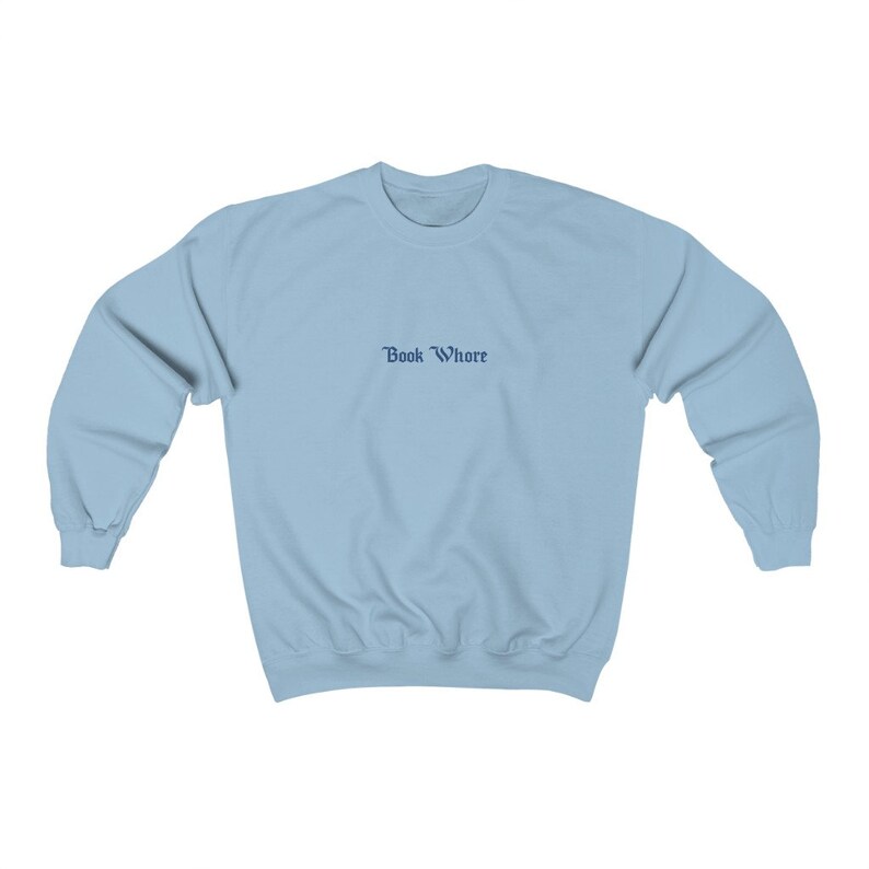 Puede incluir: Una sudadera de color azul claro con el texto "Book Whore" impreso en azul oscuro en la parte delantera.