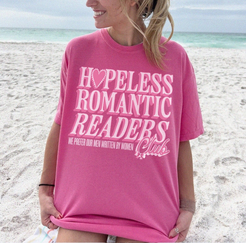 May include: A pink t-shirt with the text "Hopeless Romantic Readers Club" in white with a pink heart. The text "We prefer our men written by women" is also printed on the shirt.