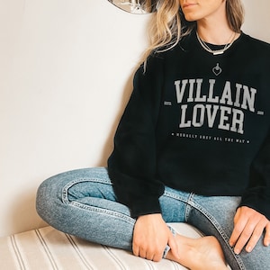 May include: Black sweatshirt with the text "VILLAIN LOVER" in white, with the text "ESTD 2020" and "MORALLY GREY ALL THE WAY" in smaller white text.