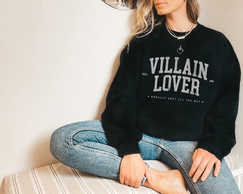 May include: Black sweatshirt with the text "VILLAIN LOVER" in white, with the text "ESTD 2020" and "MORALLY GREY ALL THE WAY" in smaller white text.