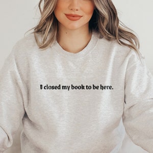 Peut inclure: Un sweat-shirt gris avec le texte "J'ai ferm&eacute; mon livre pour &ecirc;tre ici." imprim&eacute; sur le devant.