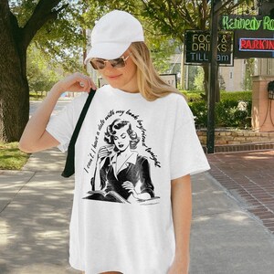May include: White oversized t-shirt with a black and white illustration of a woman reading a book and drinking from a cup. The text on the shirt reads "I can't. I have a date with my book boyfriend tonight."