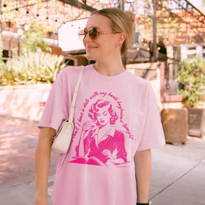 May include: Pink t-shirt with a graphic of a woman reading a book and the text "Can't I have a date with my book boyfriend tonight?"