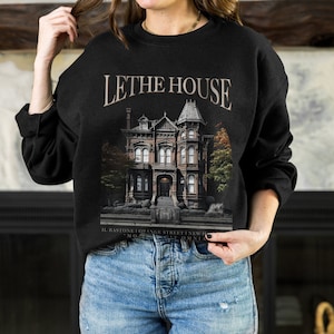 May include: Black sweatshirt featuring a graphic print of a large Victorian house with the text "Lethe House" and the address "Il Bastone 1 Orange Street, New York, NY 10013".