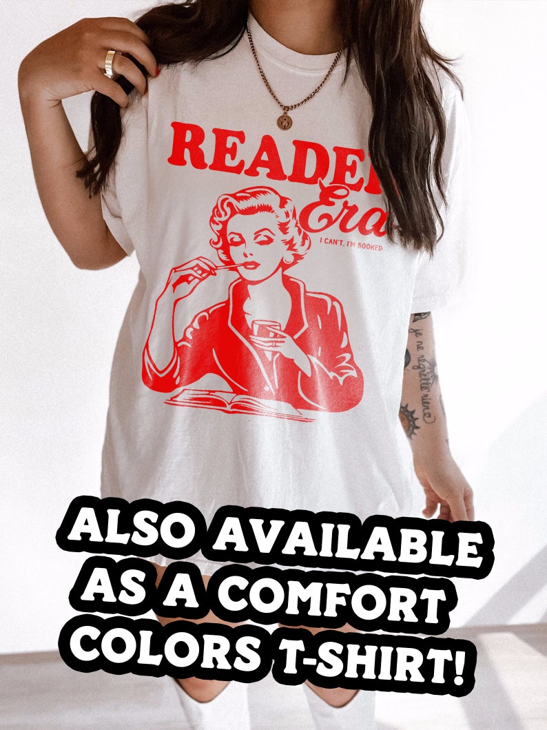 May include: White t-shirt with a red graphic of a woman reading a book and the text "Reader Era I Can't, I'm Booked". The text "ALSO AVAILABLE AS A COMFORT COLORS T-SHIRT!" is at the bottom of the image.