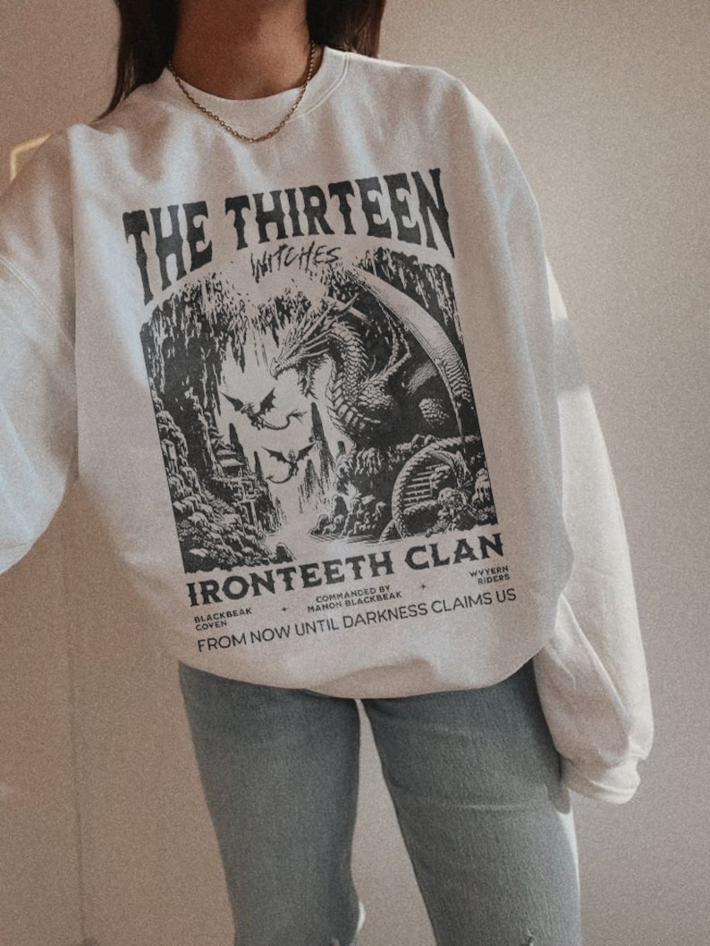 Pu&ograve; includere: Felpa bianca con una stampa grafica in bianco e nero di un drago e un testo che recita "The Thirteen Witches Ironteeth Clan Blackbeak Coven Commanded by Manon Blackbeak Wyvern Riders From Now Until Darkness Claims Us"