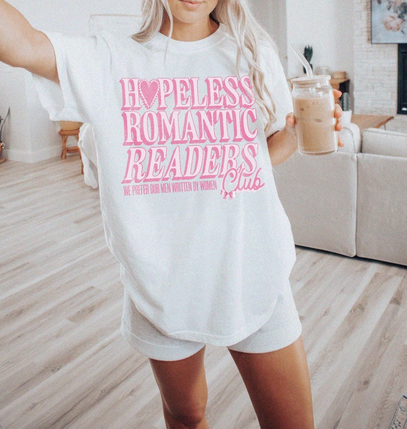May include: White t-shirt with pink text that reads "Hopeless Romantic Readers Club" and "We prefer our men written by women".