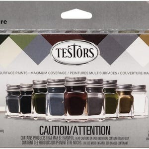 May include: A paint set with 12 jars of multi-surface paints in various colors, including black, gray, and brown. The set includes a paintbrush and is packaged in a box with the text "Paint Set" and "TESTORS".