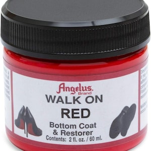 Puede incluir: Un tarro rojo de Angelus Brand "WALK ON RED" capa base y restaurador. La etiqueta incluye el texto "Contenido: 2 fl. oz. / 60 ml." e ilustraciones de tacones altos y suelas de zapatos. El tarro tiene una tapa negra.