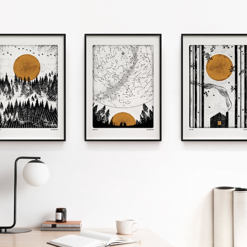 Puede incluir: Tres impresiones enmarcadas en negro con fondos blancos e ilustraciones en blanco y negro. Las impresiones presentan una escena de bosque con un sol dorado, un mapa de constelaciones con un sol dorado y una escena de bosque con un sol dorado y una peque&ntilde;a casa.