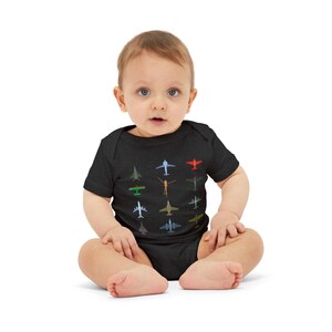 May include: A dark gray baby bodysuit featuring colorful airplane graphics. The short-sleeved one-piece garment has a crew neck and is made of a soft, comfortable material. The planes are in various colors and designs.