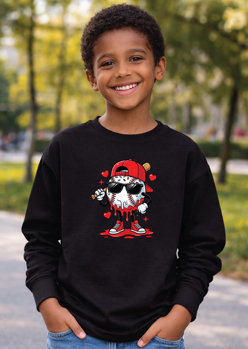Pu&ograve; includere: Felpa nera con un personaggio di baseball con occhiali da sole e un berretto rosso, che tiene una mazza. La palla da baseball ha un design a goccia con dettagli rossi ed &egrave; circondata da cuori. La felpa &egrave; indossata da un bambino sorridente.
