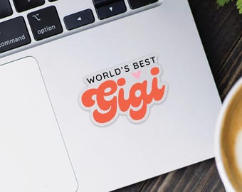 May include: A white laptop with a sticker that says "World's Best Gigi" in orange letters with a pink heart.