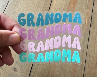 May include: Four clear stickers with the word "Grandma" in bubble letters. The stickers are layered on top of each other, with each layer in a different color: teal, purple, pink, and light blue.