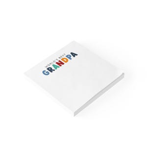 May include: A white notepad with the text "World's Best Grandpa" in colorful letters. The notepad is stacked and angled on a white background.