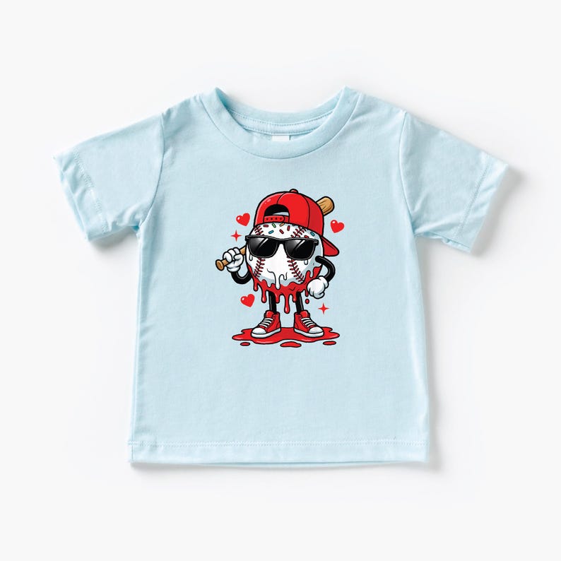 Op de afbeelding: Lichtblauw peuter T-shirt met een honkbal karakter met een zonnebril, een rode pet en rode sneakers. De honkbal heeft een knuppel en is omringd door harten en druipende rode accenten. Het ontwerp is gecentreerd op het shirt.