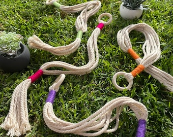 May include: Five macrame plant hangers with wooden rings. The hangers are made of natural cotton rope and have colorful accents in pink, green, orange, and purple.