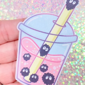 May include: A pink and blue bubble tea cup with a yellow straw and black and white fuzzy balls inside. The text "domi" is at the bottom of the cup.
