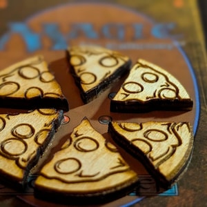 May include: Wooden pizza slices with a dark brown outline and light brown interior, arranged in a circle. Each slice has a dark brown circle design. The pizza slices are on a Magic card.