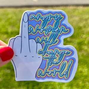 May include: A white sticker with a raised middle finger and the text "angry women will change the world" in a rainbow font.