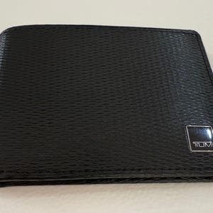 Cartera Tumi de piel negra para hombre, con seis ranuras para tarjetas de crédito, en perfecto estado.