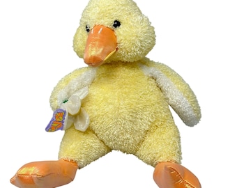 May include: A yellow plush duck with a white bib and orange feet. The duck is holding a white flower with a purple butterfly on it.